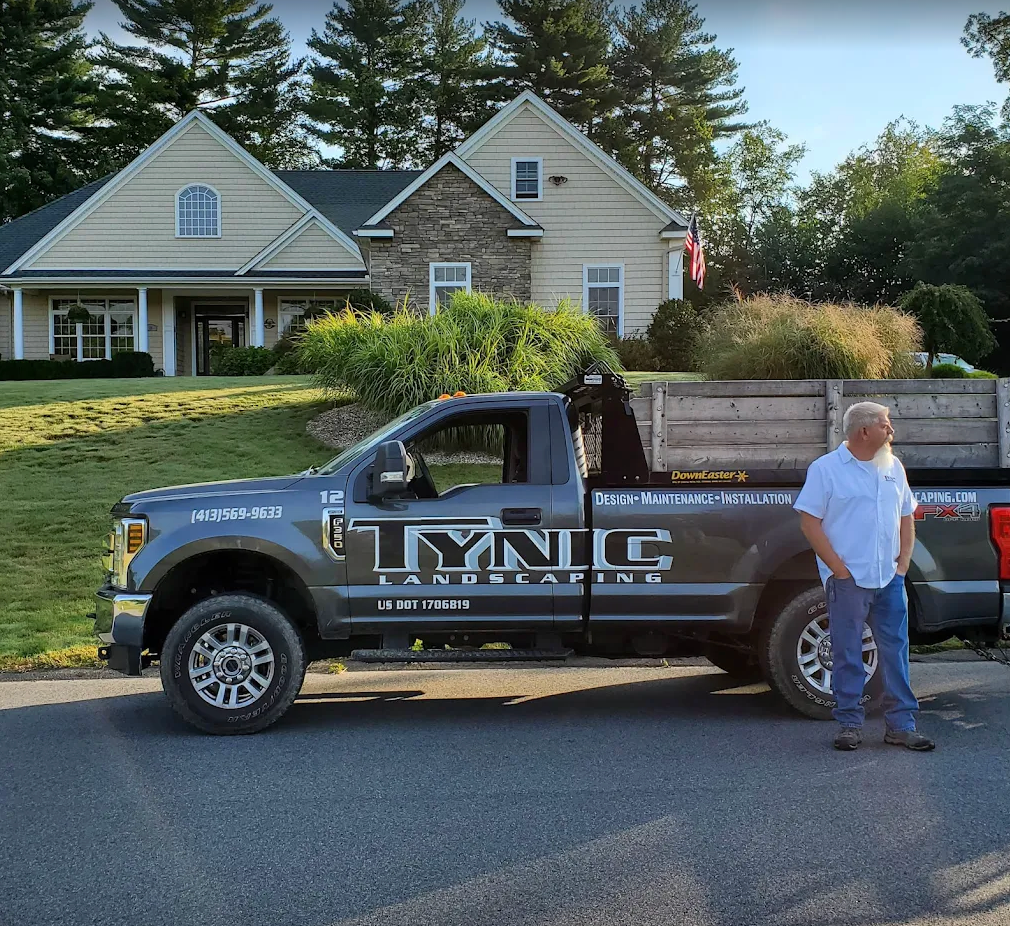 Tynic Landscaping truck parked at a client's home with a crew member alongside